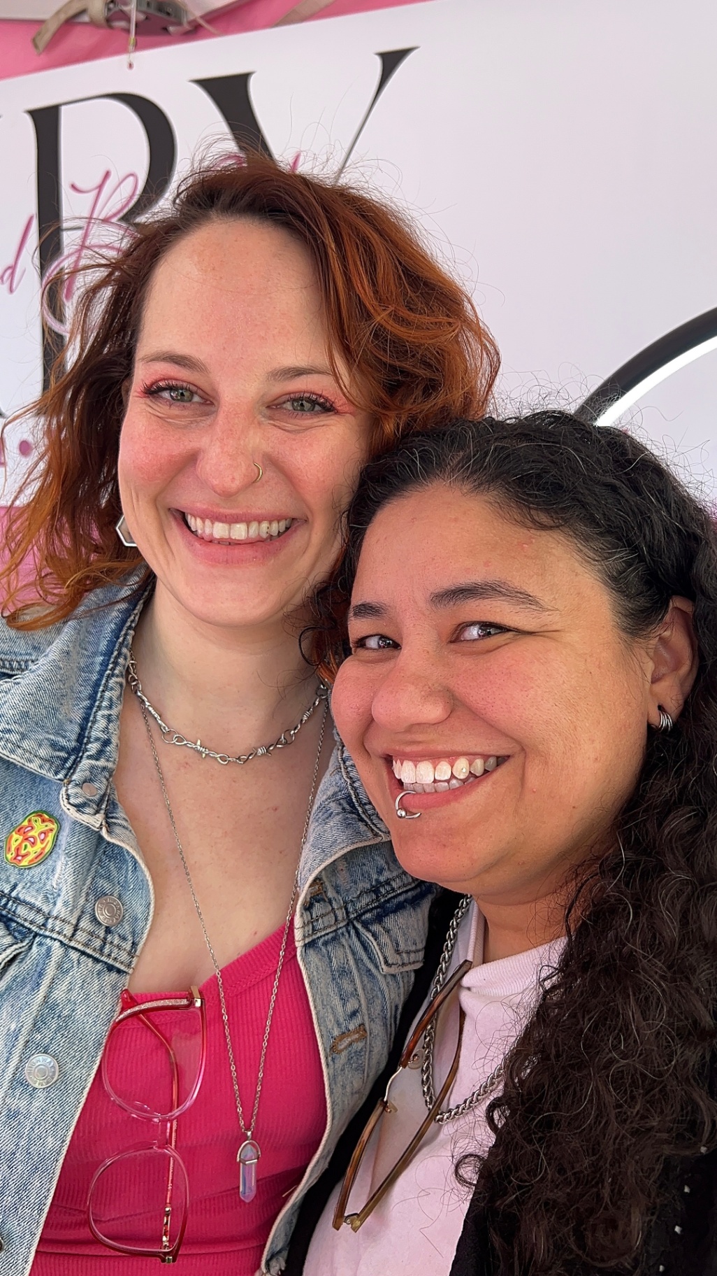 Two guests smiling in front of the Iced By Yana banner