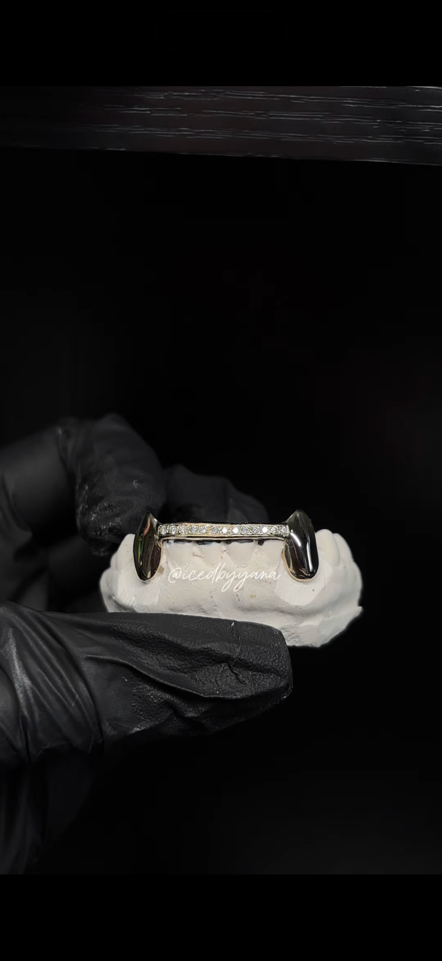 Diamond bar with gold fang caps on a dental model